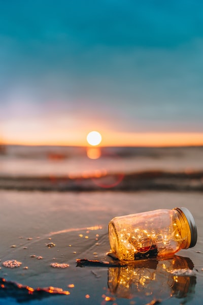 透明玻璃mason jar日落在沙滩上
